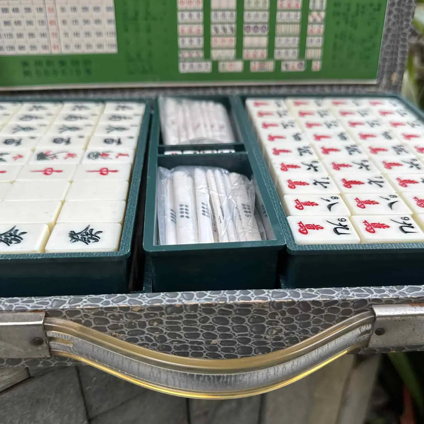 Open mahjong set with tiles and rules in a decorative case.